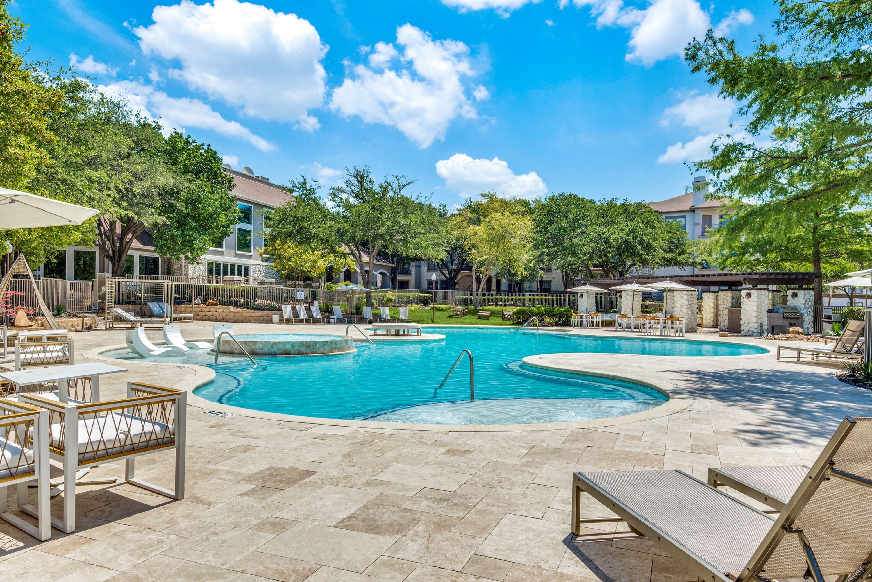 Stunning resort-style swimming pool with elegant lounging chairs, surrounded by lush greenery and contemporary architecture.