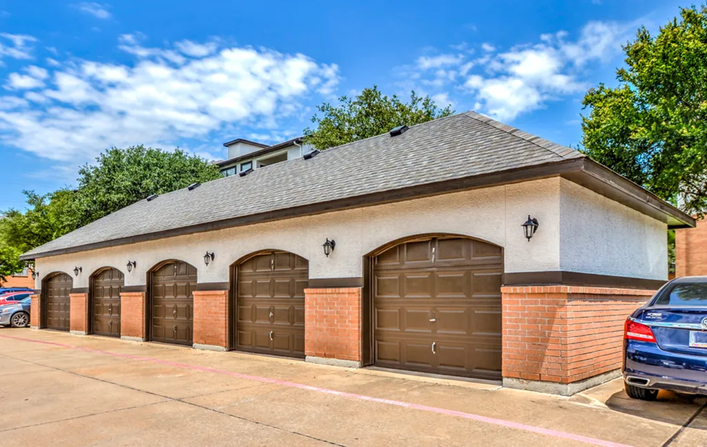 Charming multi-garage unit with brick accents, nestled under a vibrant blue sky, offering ample parking space.