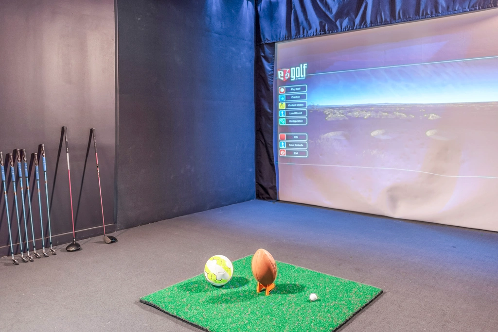 Luxurious indoor golf and sports simulator room with virtual golf experience, sleek design, and modern amenity in an upscale apartment setting.