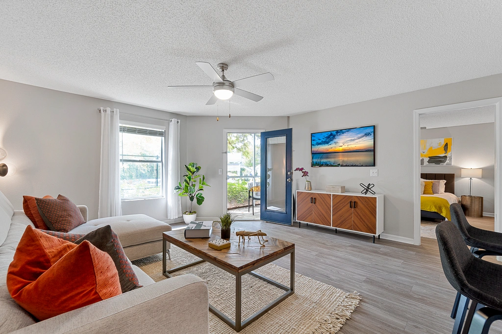 Modern kitchen with breakfast bar seating, featuring white cabinetry, stainless steel appliances, and a clean, open pass-through design into the living area.