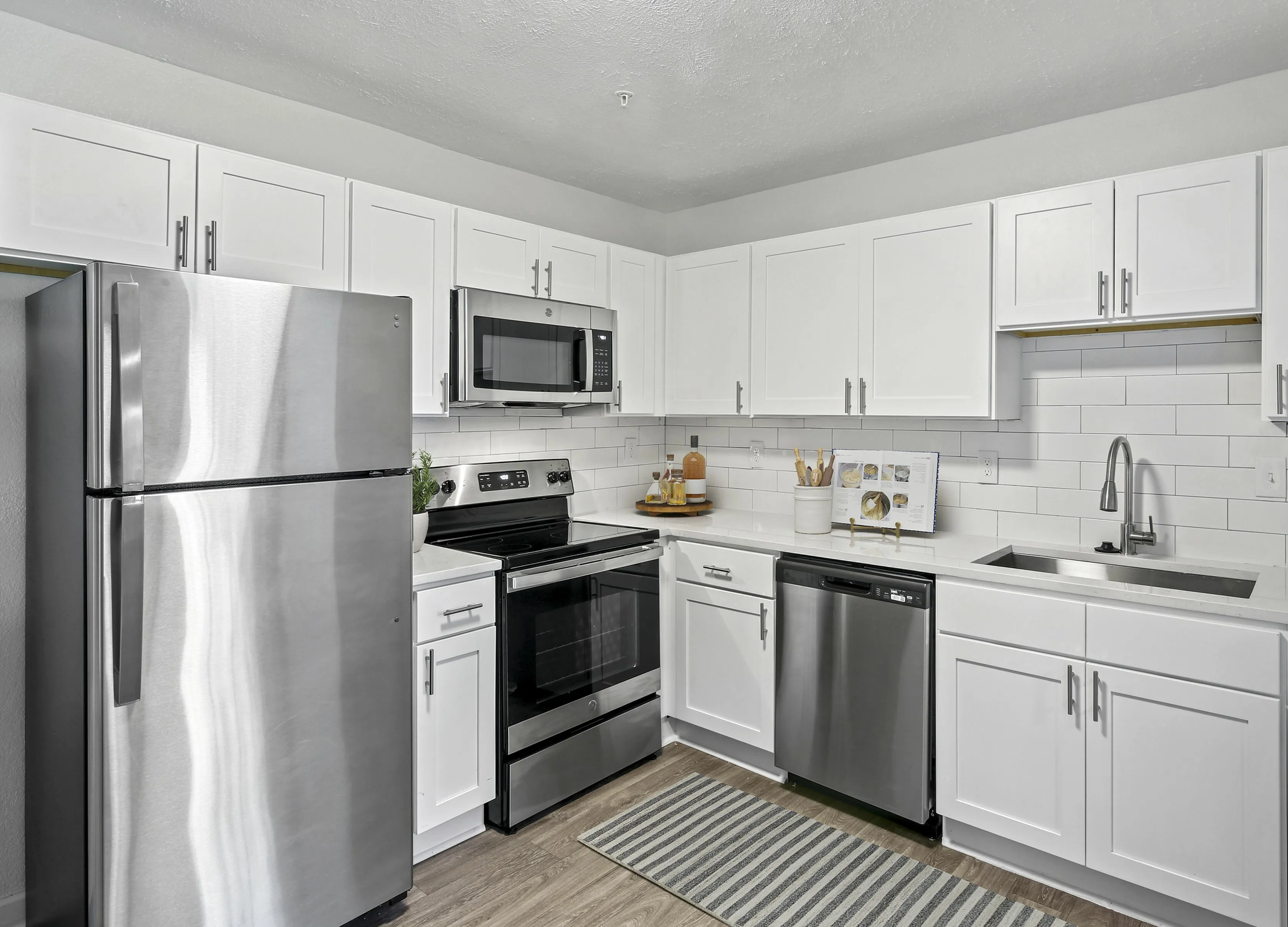 Modern kitchen with sleek stainless steel appliances, white cabinetry, and stylish subway tile backsplash.