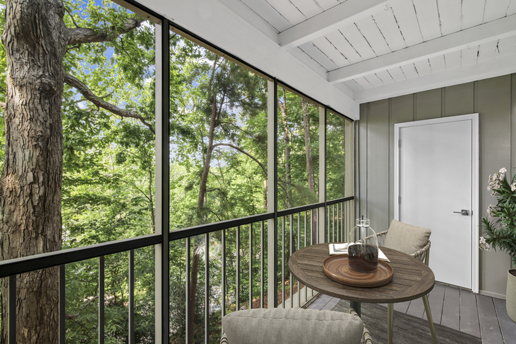Charming screened-in balcony offering serene forest views, perfect for relaxation.