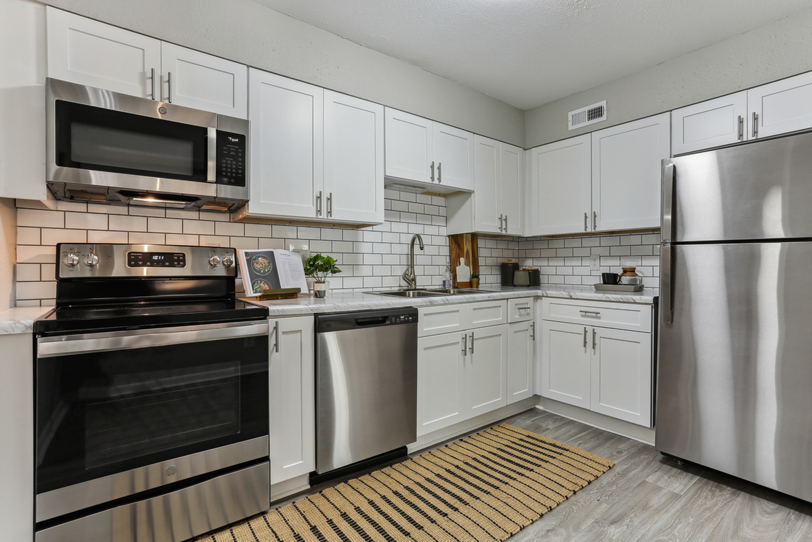Modern kitchen with sleek stainless steel appliances, elegant white cabinetry, and a trendy subway tile backsplash.
