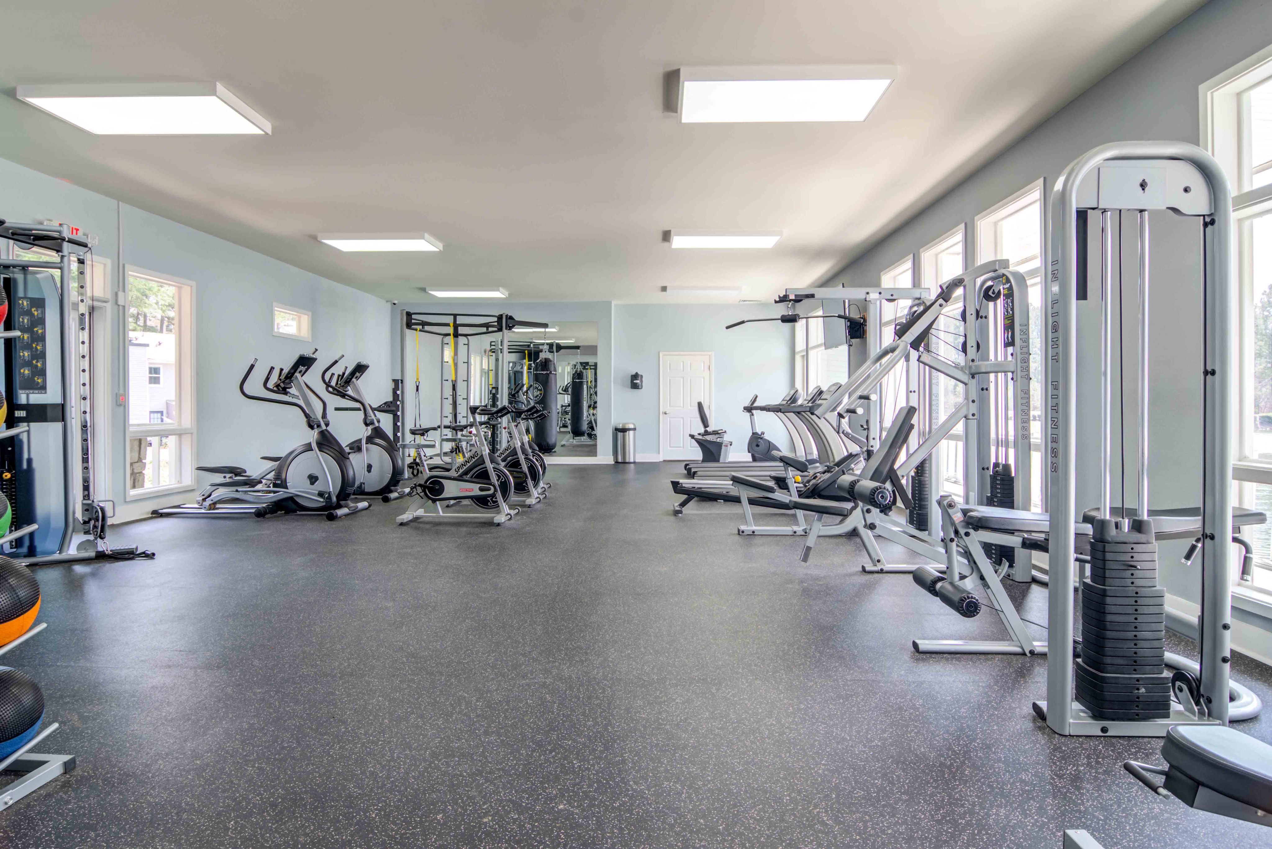 Modern fitness center equipped with state-of-the-art exercise machines, offering a light-filled space for a comprehensive workout experience.