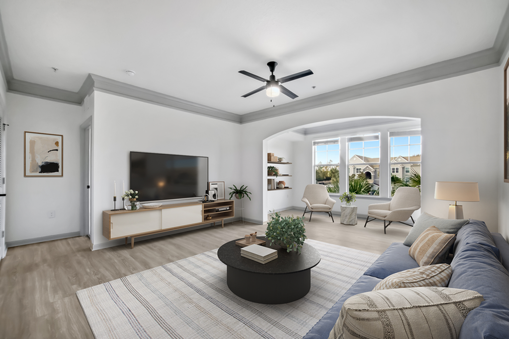 Elegant living room with modern decor, large flat-screen TV, cozy seating area, and bright windows offering scenic views.