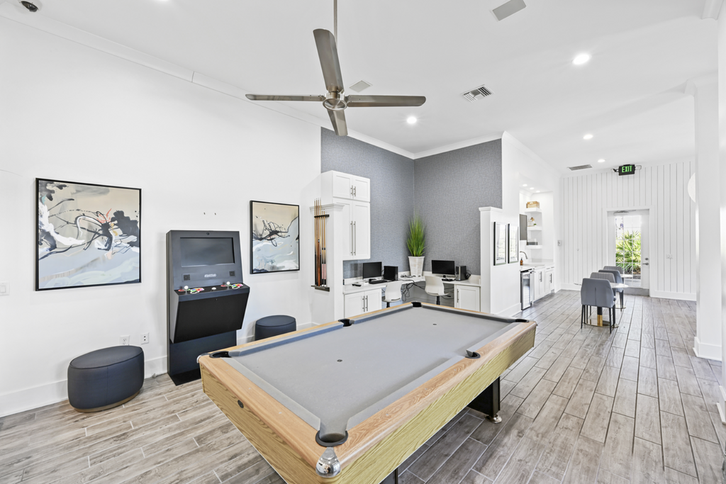 Spacious resident activity room featuring a sleek pool table, arcade machine, modern seating area, and stylish decor with a contemporary vibe.