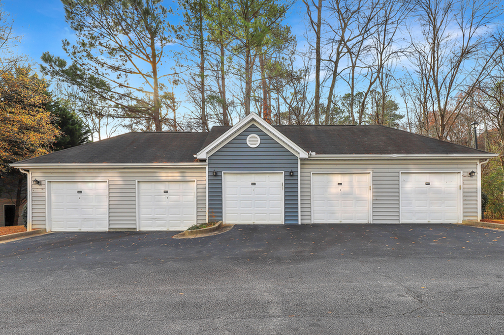 Charming residential garage block with multiple doors against a serene tree-lined backdrop.