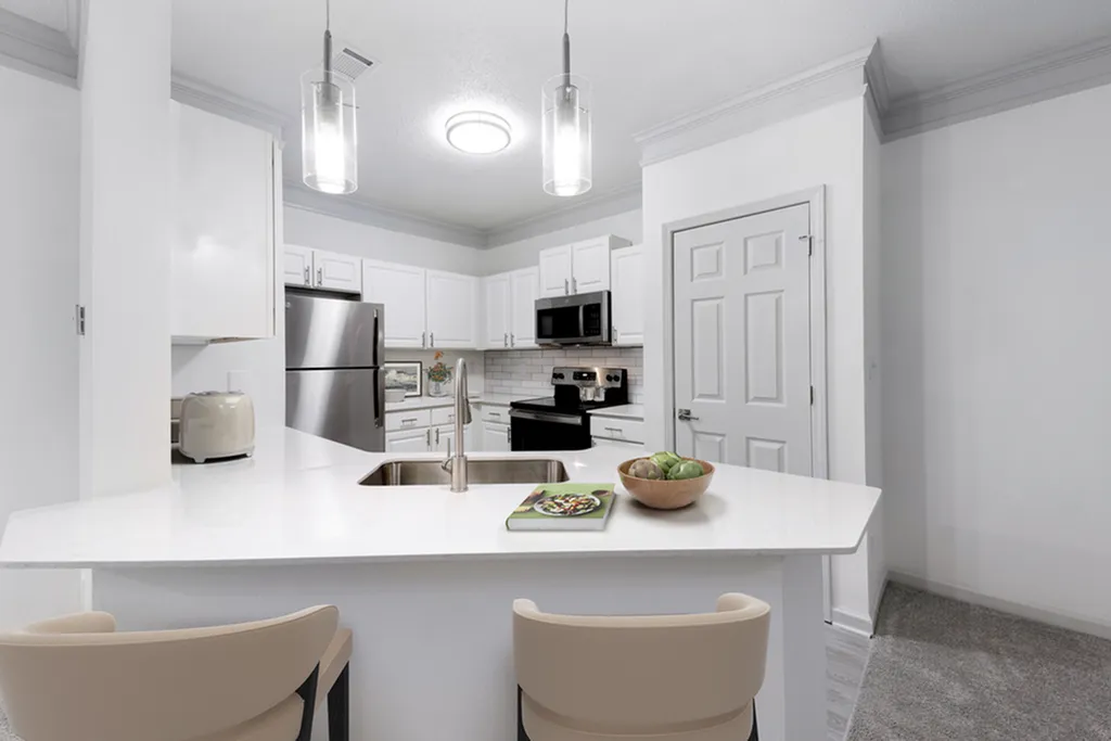 Modern kitchen with sleek stainless steel appliances, elegant pendant lighting, and a spacious breakfast bar with seating.