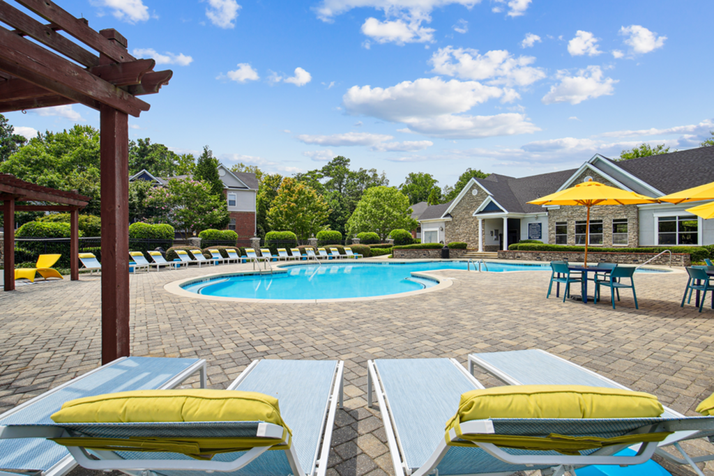 Inviting community pool area with sun loungers, vibrant yellow umbrellas, and a picturesque patio, perfect for relaxation and social gatherings.