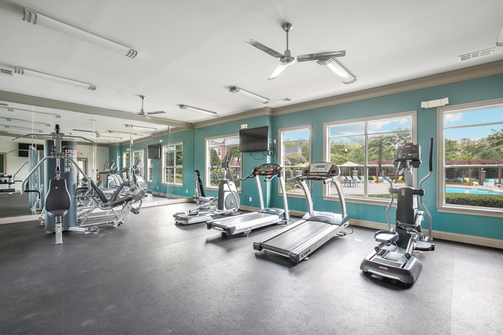 Bright and modern fitness center with state-of-the-art exercise equipment and large windows offering poolside views.