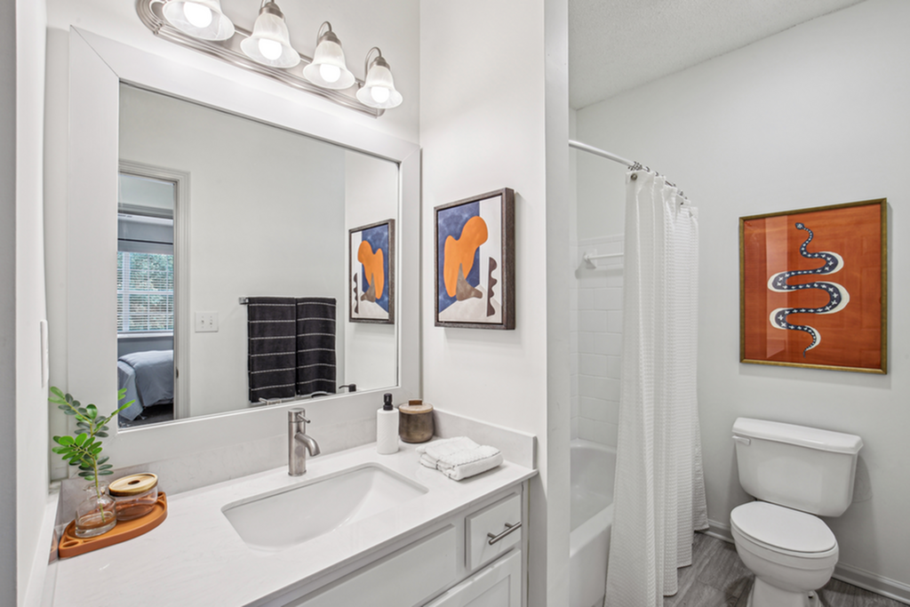 Modern bathroom with sleek white fixtures, elegant lighting, and contemporary artwork, showcasing a serene and stylish design.