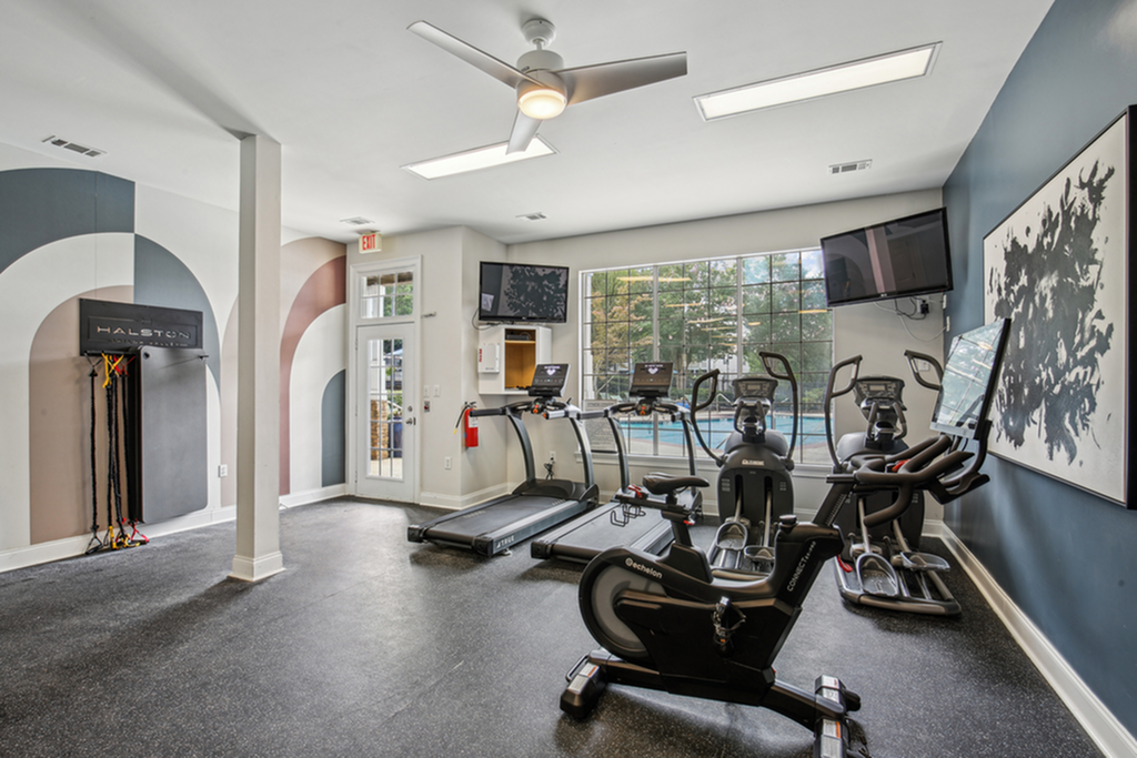 Modern fitness center with state-of-the-art equipment, large windows, and stylish wall art, creating an inviting workout atmosphere.