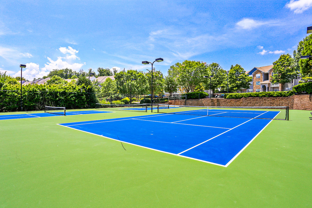 Vibrant and inviting outdoor tennis courts surrounded by lush greenery, perfect for recreational activities in a picturesque residential setting.