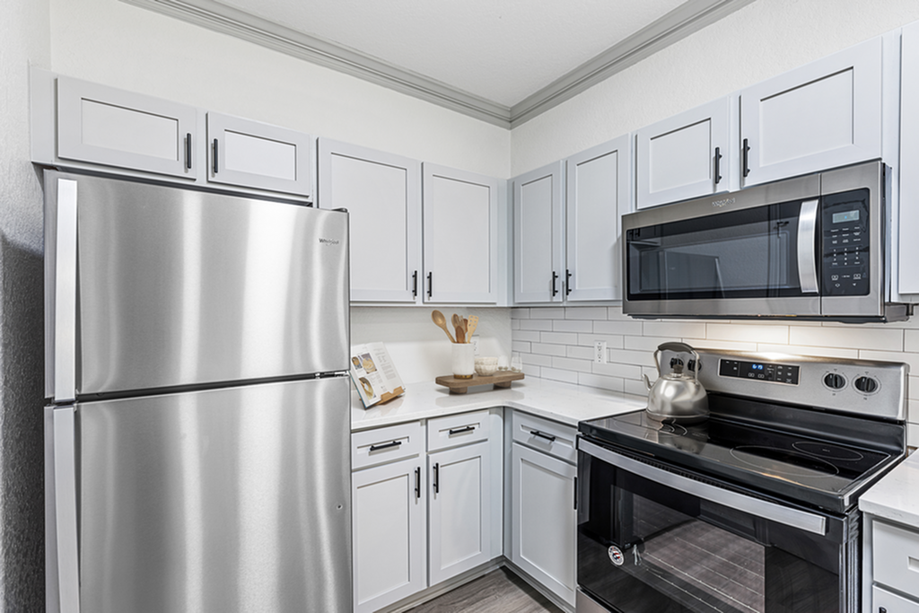 Modern kitchen with sleek stainless steel appliances, white cabinetry, and elegant subway tile backsplash.