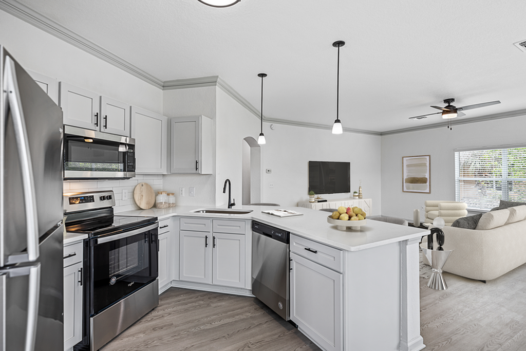 Modern open-plan kitchen and living area with sleek appliances, elegant white cabinets, and abundant natural light.