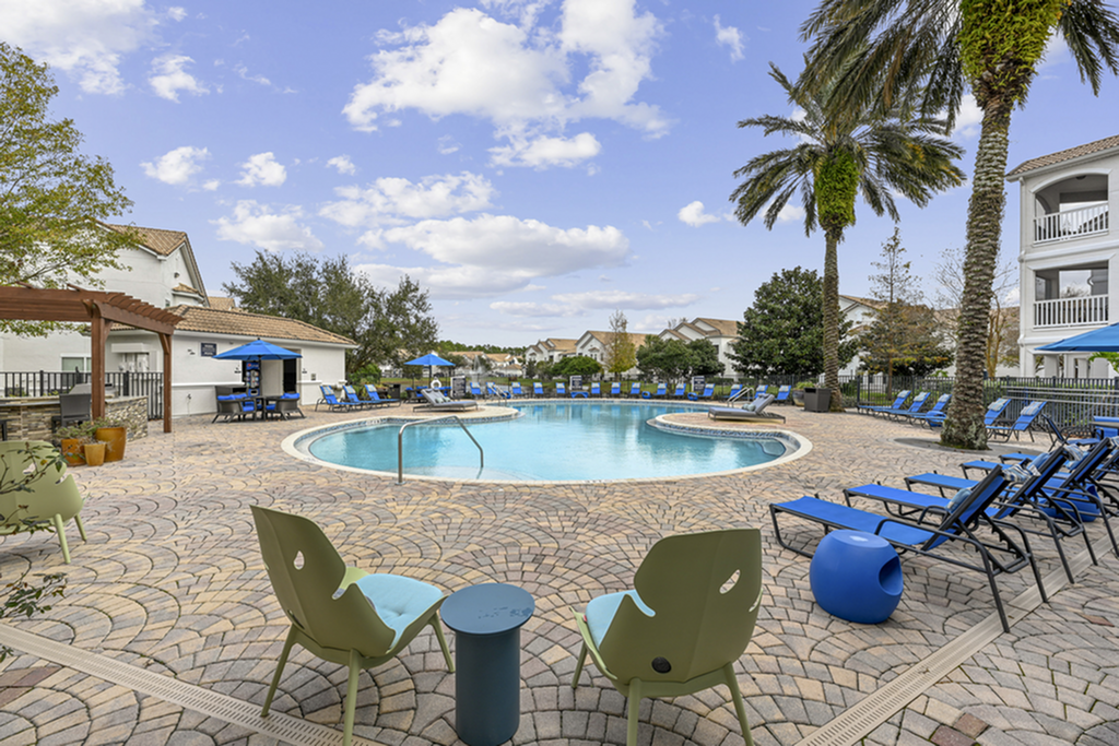Inviting outdoor pool area with elegant palm trees, stylish lounge chairs, and vibrant umbrellas under a clear blue sky.