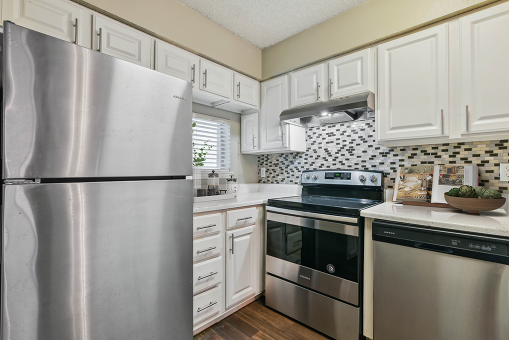 Modern kitchen with sleek stainless steel appliances, elegant white cabinetry, and a stylish mosaic backsplash.
