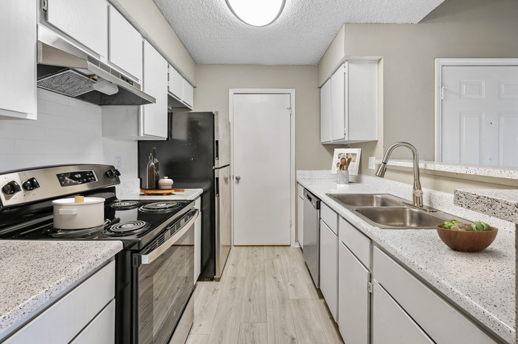 Modern kitchen with sleek white cabinetry, stainless steel appliances, and elegant granite countertops with decorative touches.