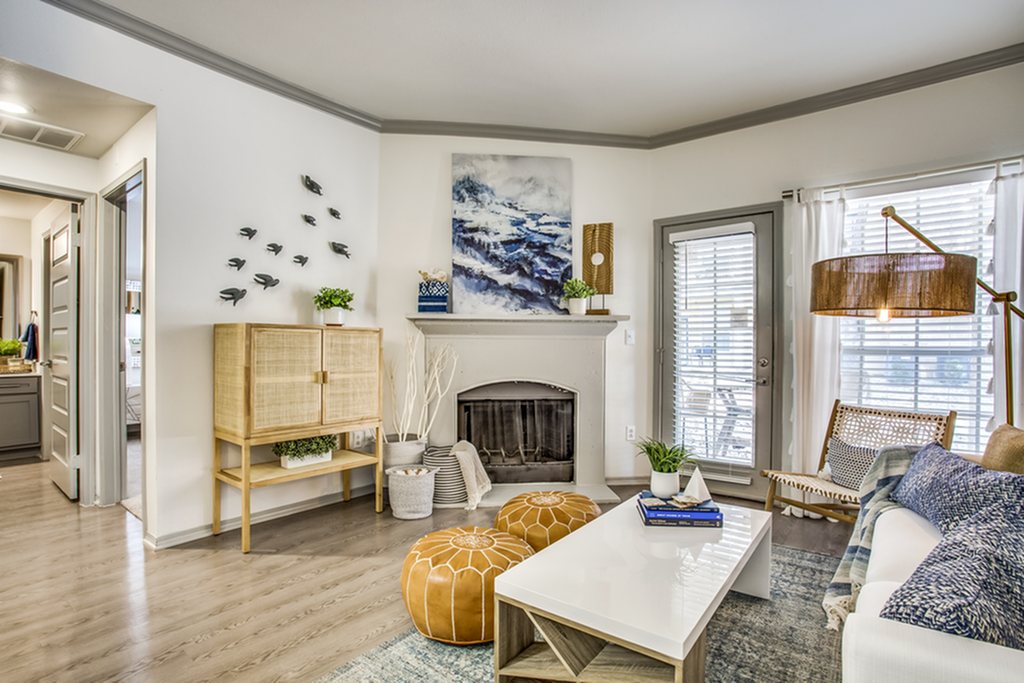 Chic living room with modern decor, featuring a cozy fireplace, stylish furniture, and abundant natural light through large windows.