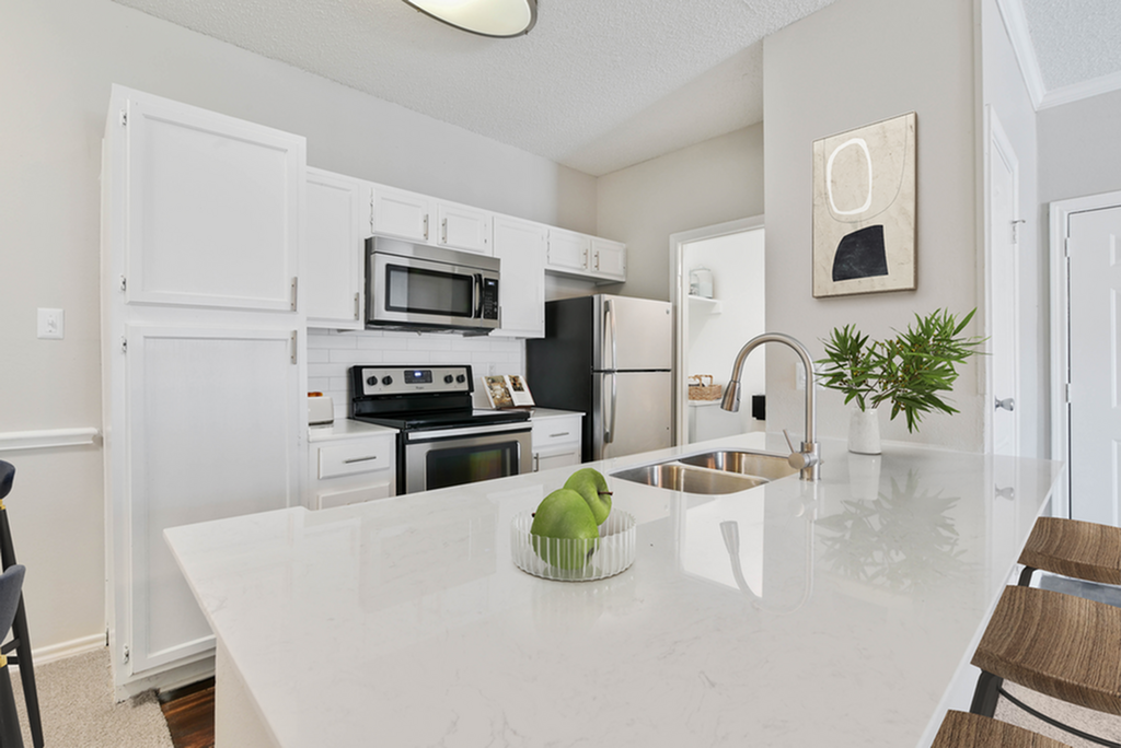 Modern kitchen with sleek white cabinetry, stainless steel appliances, and a chic island countertop accented by fresh greenery.
