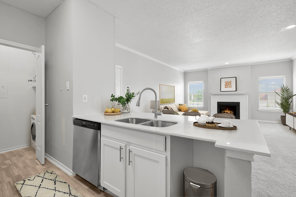 Modern open-concept kitchen featuring sleek stainless steel appliances, leading into a cozy living room with a fireplace and abundant natural light.
