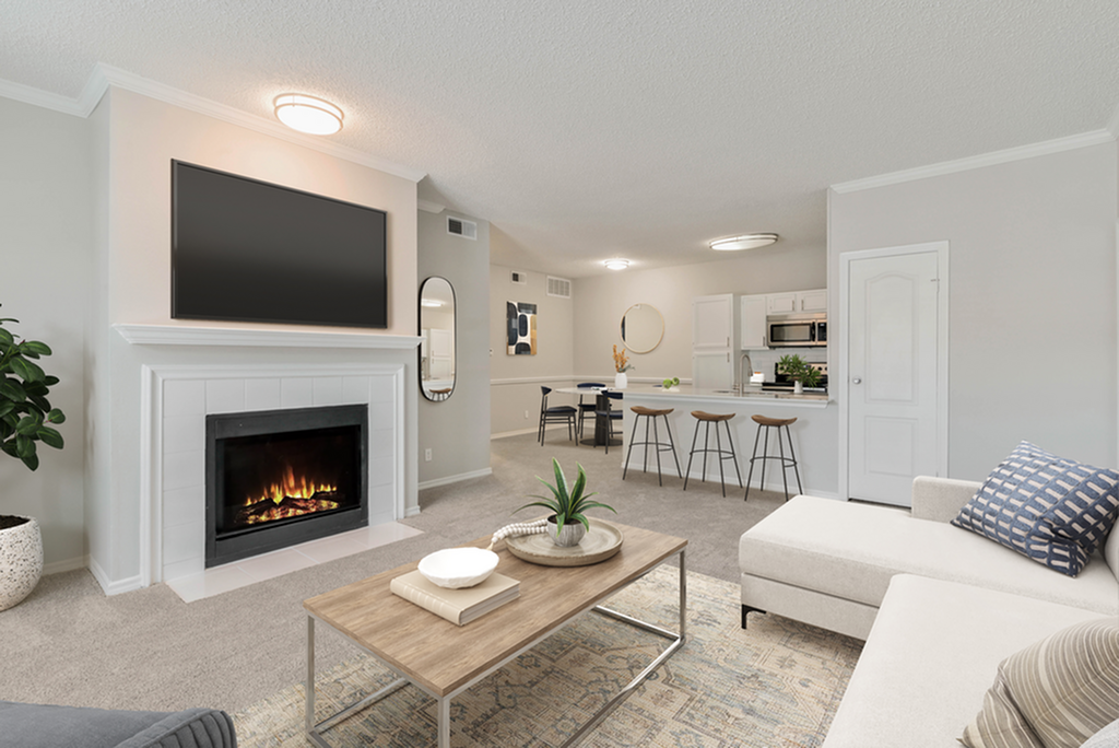 Inviting living room with a cozy fireplace and modern decor, leading to an open-concept kitchen with bar seating.