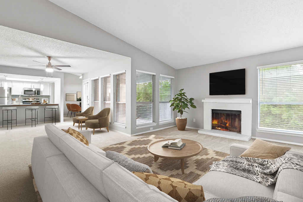 Elegant open-plan living space featuring a cozy fireplace, large windows, and a modern kitchen in a bright, inviting setting.