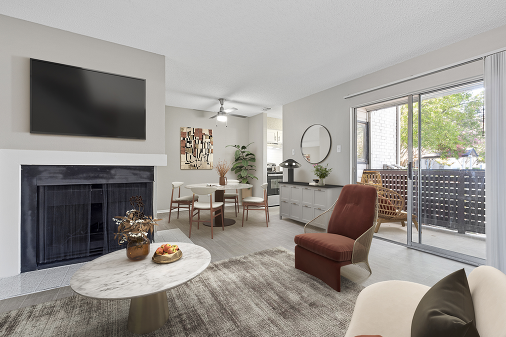 Bright and modern living room with elegant furnishings, a cozy fireplace, and floor-to-ceiling windows leading to a charming patio view.