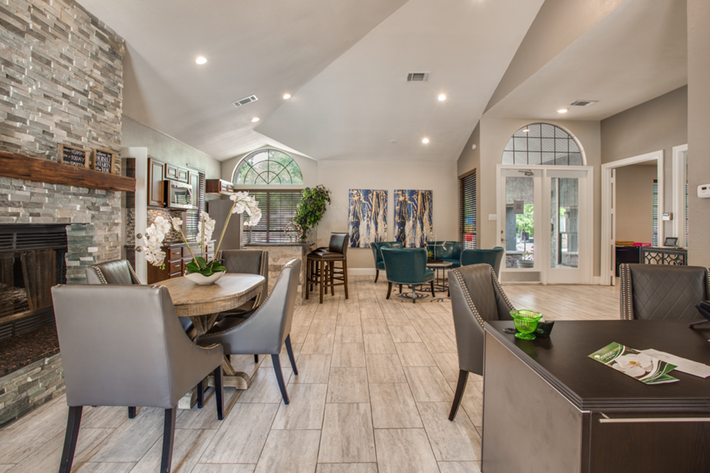 Elegant clubhouse lounge with vaulted ceilings, modern stone fireplace, cozy seating, and vibrant decor.
