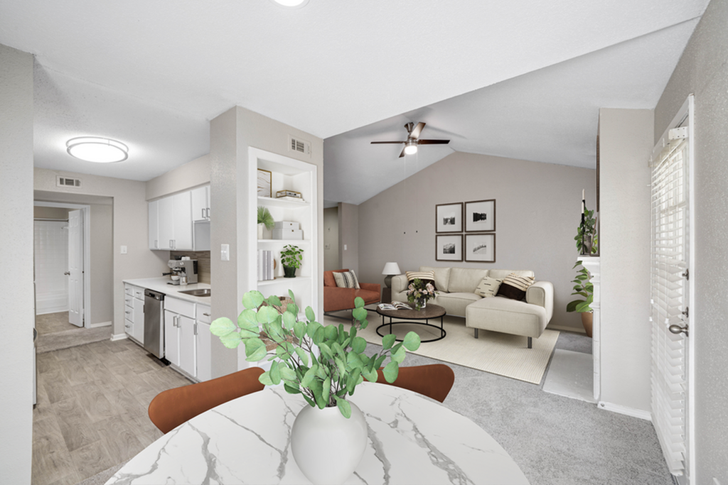 Bright and inviting open-plan living space featuring modern kitchen, cozy lounge area with a plush corner sofa, and elegant dining table adorned with greenery.