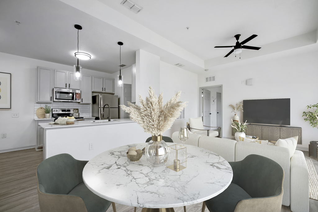 Modern open-concept apartment featuring a sleek kitchen with stainless steel appliances, cozy living area, and stylish marble dining table.