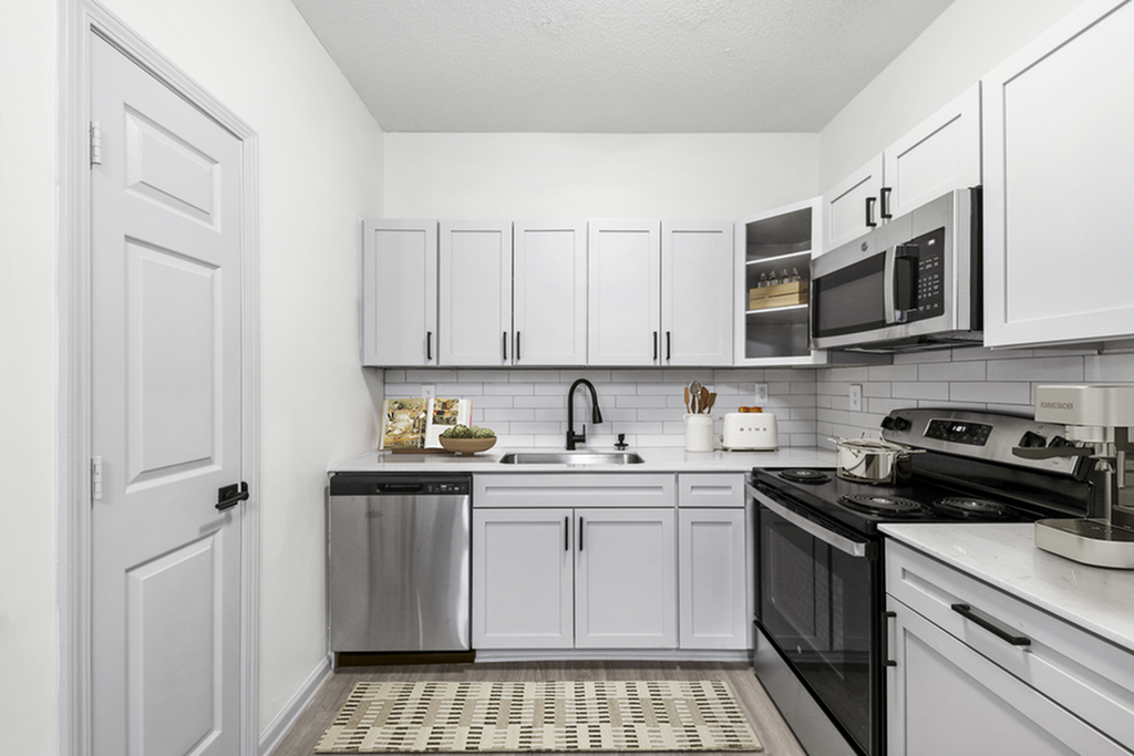 Modern kitchen with sleek white cabinetry, stainless steel appliances, and stylish subway tile backsplash.