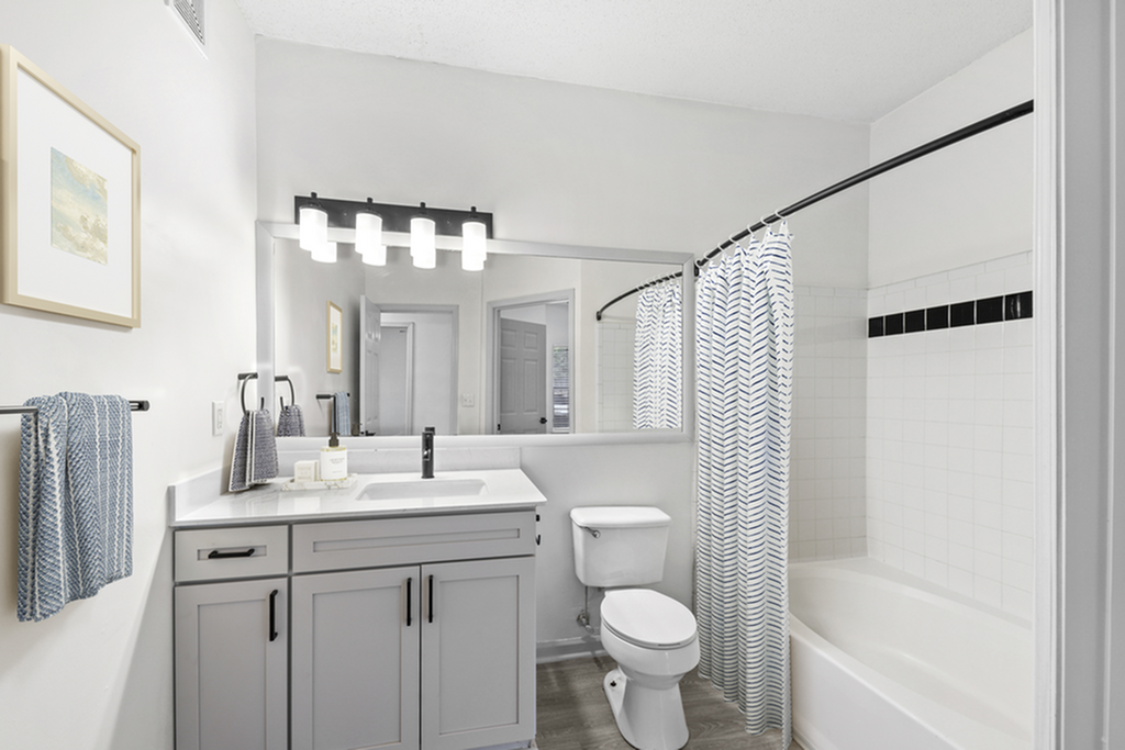 Elegant bathroom featuring modern vanity, chic lighting, and a stylish shower with patterned curtain.