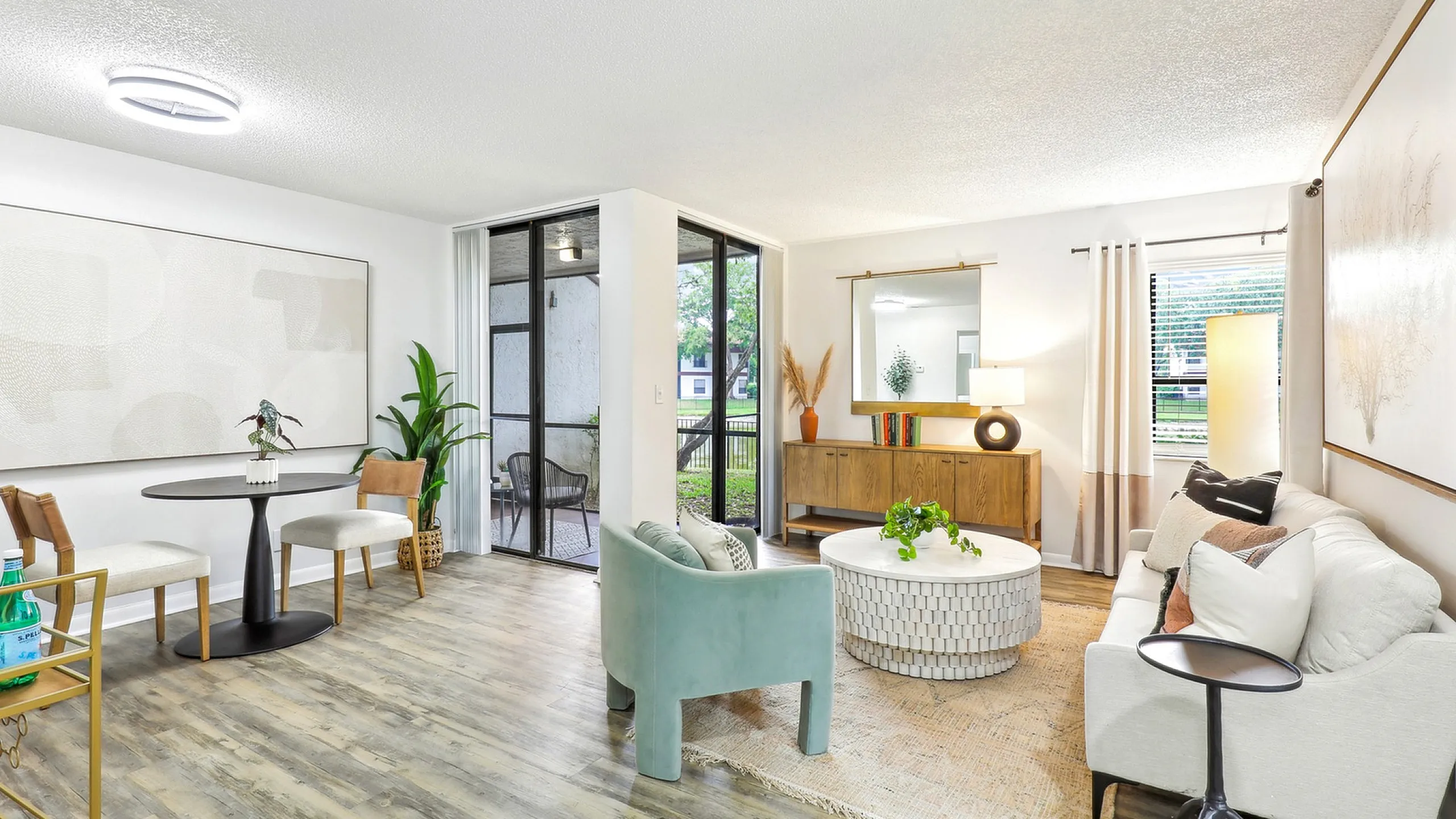 Renovated living room with floor to ceiling glass patio doors, wood flooring, furniture