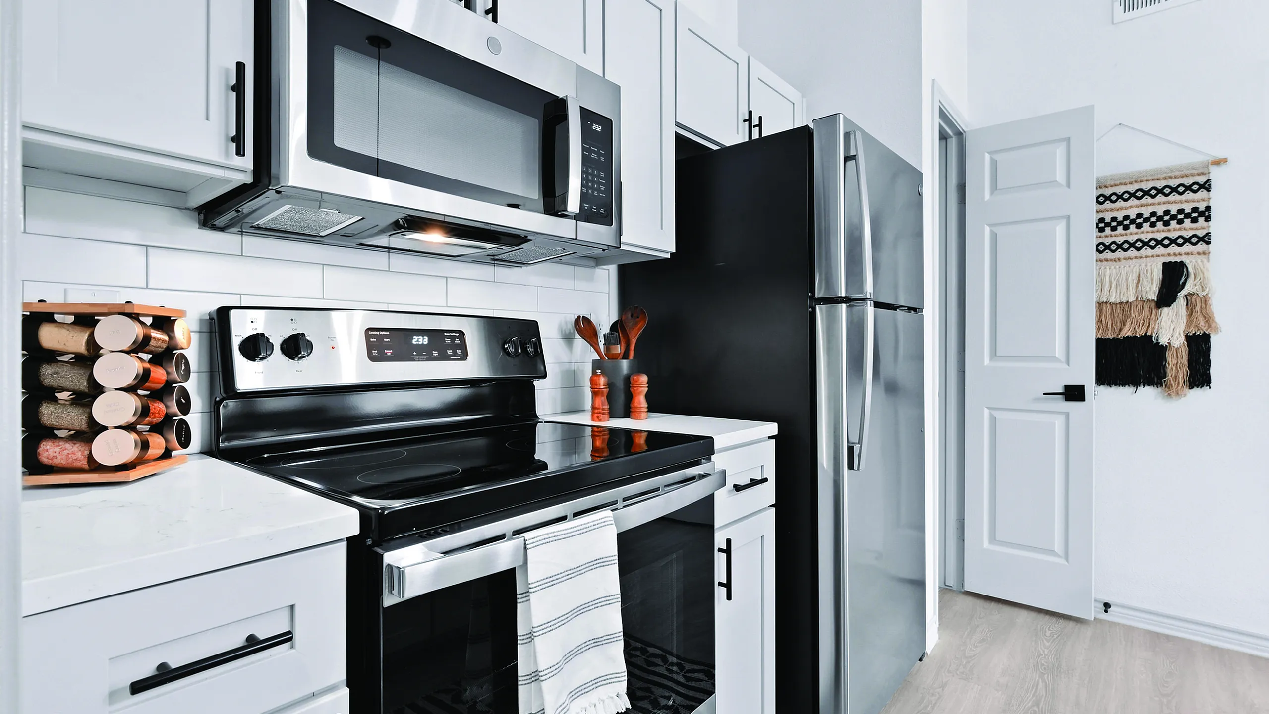 Sleek modern kitchen with stainless steel appliances, elegant white cabinetry, and a spice rack for gourmet cooking.