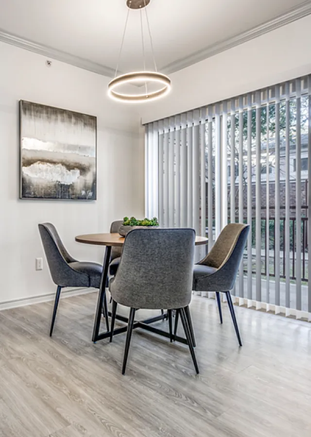 Modern apartment interior showcasing a bright dining area with sleek furniture and an elegant bedroom visible through an open door, featuring contemporary decor and inviting ambiance.