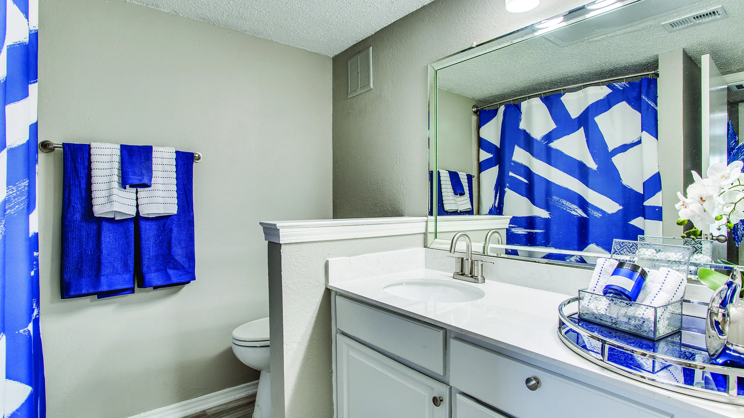 Modern bathroom with vibrant blue accents, elegant white vanity, and stylish lighting.