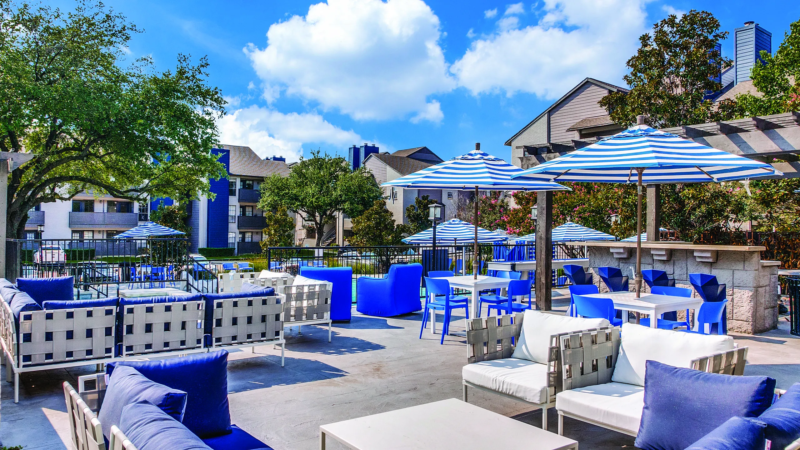 Vibrant outdoor seating area with stylish blue and white umbrellas, perfect for relaxation and gatherings under a sunny sky.