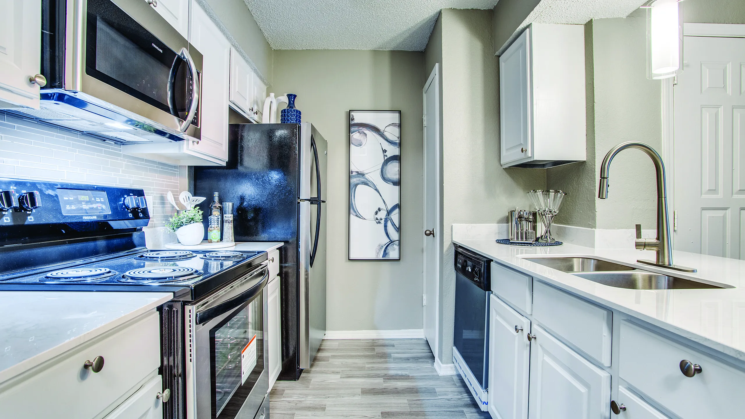 Modern kitchen with sleek stainless steel appliances, white cabinetry, and chic lighting, perfect for culinary enthusiasts.