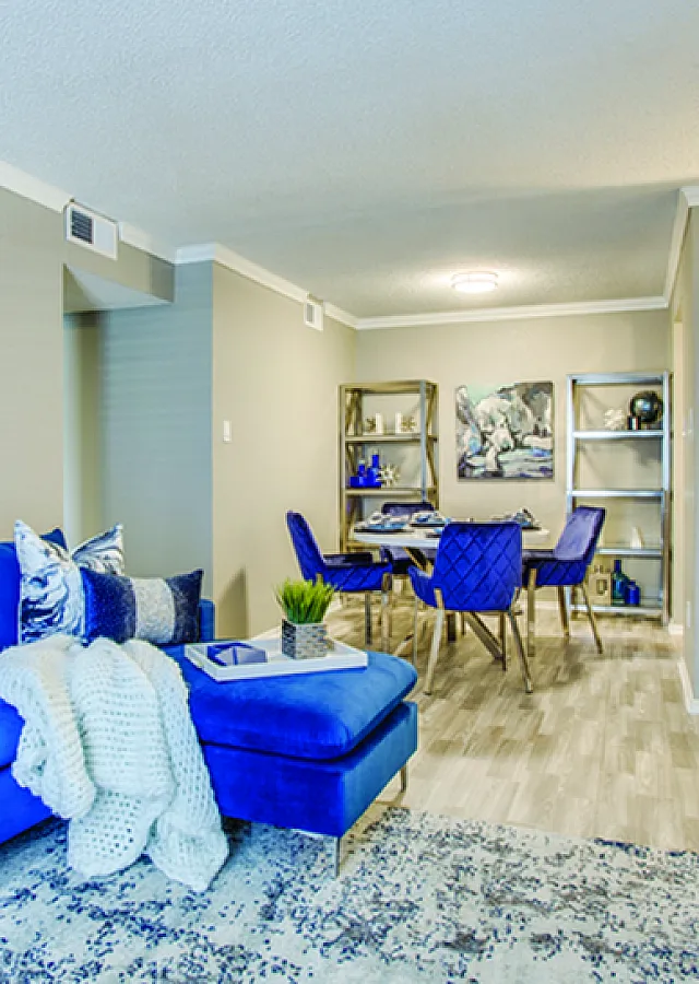 Modern living space with vibrant blue furniture, stylish dining area, and open kitchen, showcasing a blend of comfort and contemporary design.