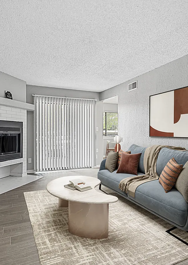 Elegant living room with chic grey sofa, modern art, cozy fireplace, and floor-to-ceiling windows for natural light.
