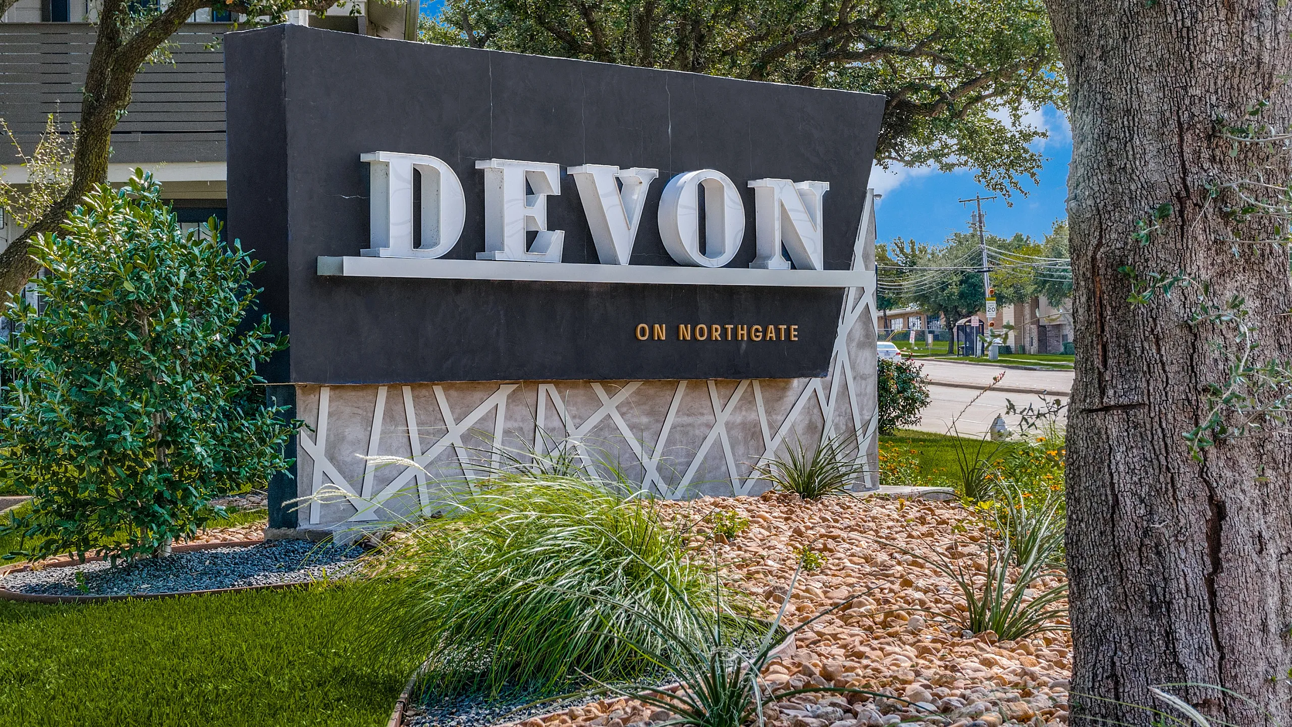 Inviting entry sign for Devon on Northgate, surrounded by lush greenery and modern landscaping.