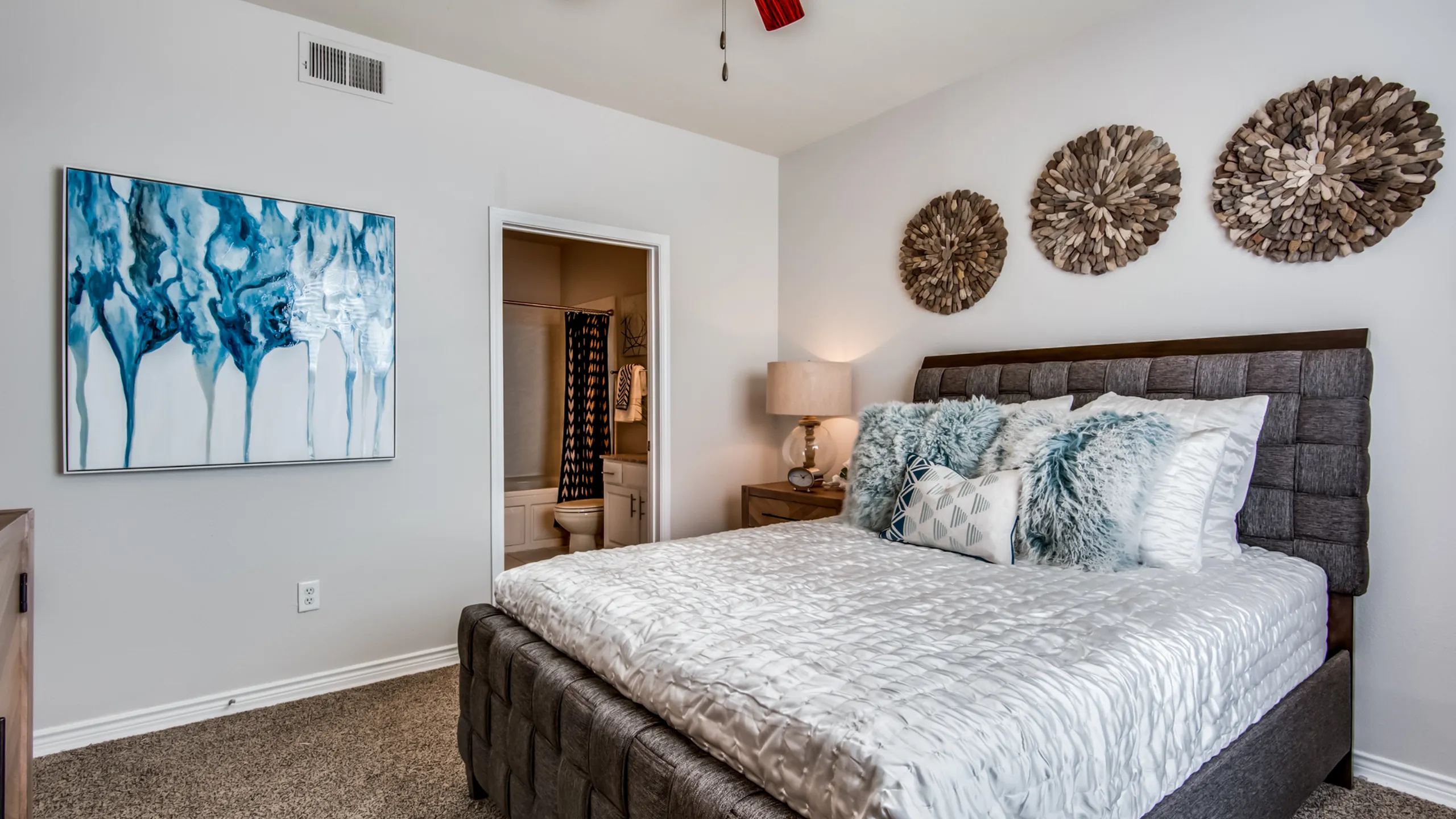 Elegant bedroom featuring a plush bed, cozy pillows, and stylish wall art, plush carpeting and an ensuite.