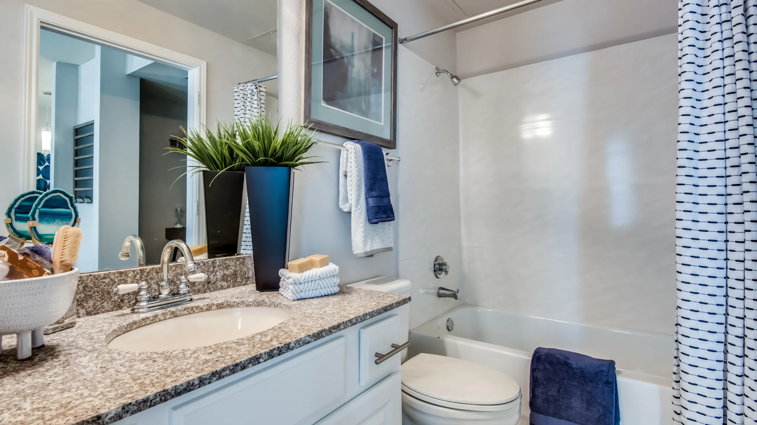 Modern bathroom featuring elegant granite countertops, stylish decor, and a sleek shower-tub combination.