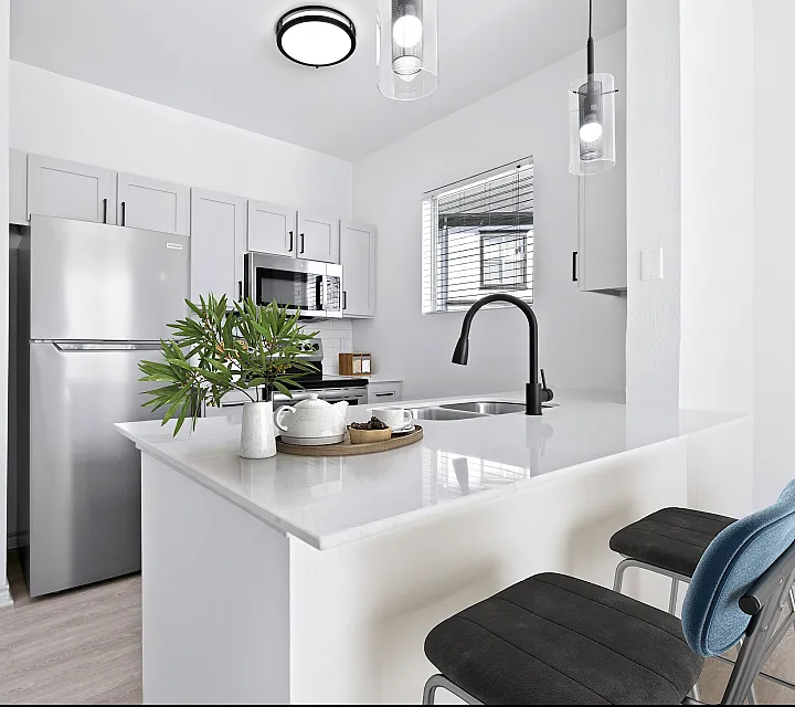 Contemporary kitchen with sleek stainless steel appliances, elegant white cabinets, and a chic breakfast bar adorned with stylish pendant lighting.