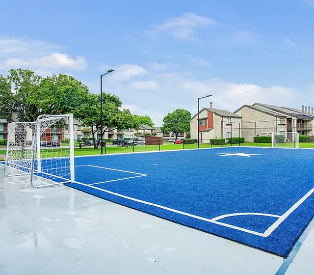 A blue outdoor sport court with soccer nets and artificial turf.