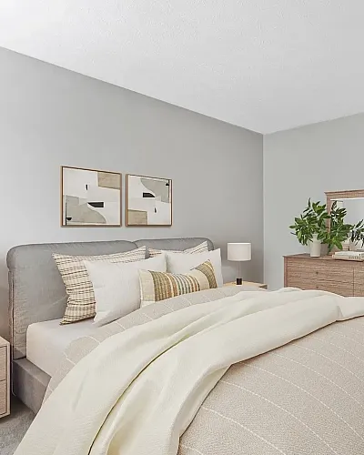 Spacious apartment bedroom with plush carpeting, modern decor, large bed, natural light, and en-suite bathroom access.