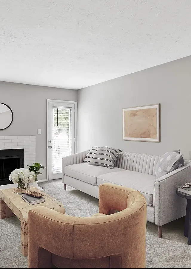 Stylish apartment living room with modern furnishings, decorative fireplace, wall-mounted TV, large windows, and access to private patio or balcony.