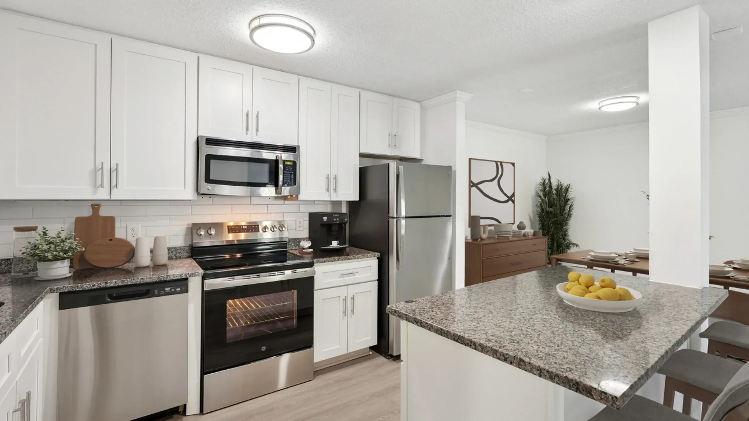 Modern kitchen with sleek stainless steel appliances, granite countertops, and elegant white cabinetry adjacent to a stylish dining area.