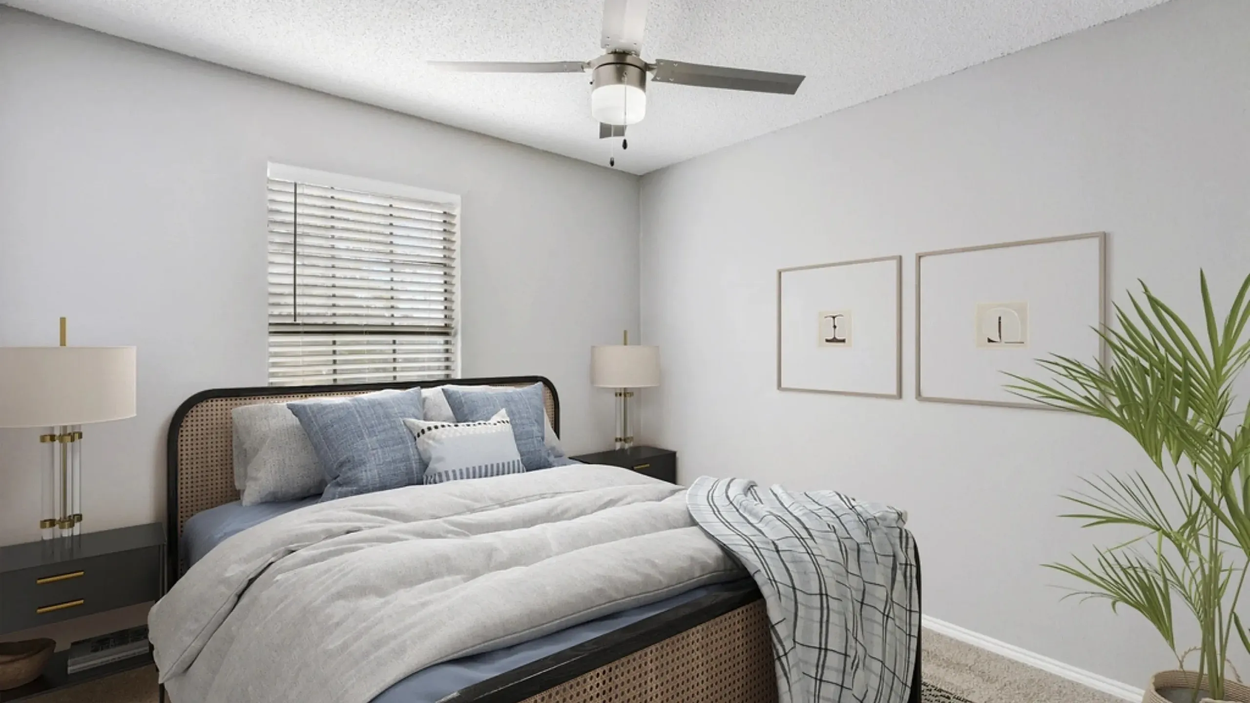 Cozy bedroom with plush carpeting, a neatly made bed with soft gray and blue bedding, and a ceiling fan with light fixture. Features include a window with blinds, nightstands with lamps, framed wall art, and a potted plant for a clean, mode